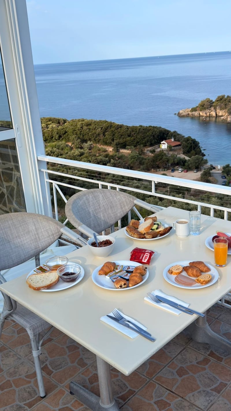 Breakfast table with coffee, fruit and pastries overlooking the Ionian Sea at Hotel Agia Paraskevi